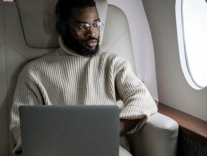 A man seated on an airplane engrossed in his laptop