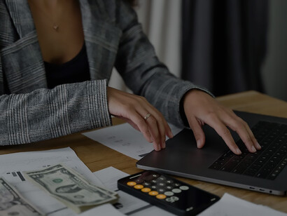 Delving into financial empowerment, an African woman contemplates amidst coins and technology in her workspace