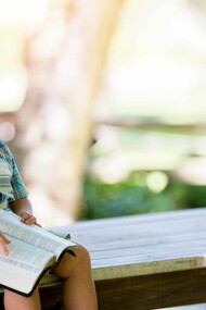 A child barely holding onto his book as he smiles and laughs uncontrollably