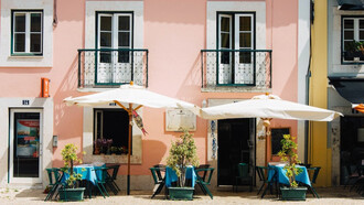 Adoring Lisbon's charms, two white patio umbrellas grace a pink and white painted building, Portugal