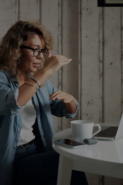 A woman is video chatting with another woman with her coffee in front of her computer