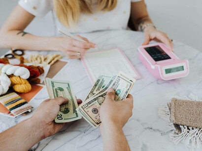 A woman calculating and taking notes of the funds coming into her start-up