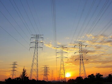 High-voltage power transmission lines at sunset, representing the vulnerability of critical infrastructure to AI-driven cyberattacks