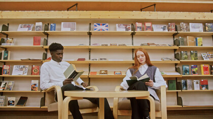 In a quiet corner of the library, two readers immerse themselves in the transformative power of knowledge, proving that true growth begins with intentional investment in oneself