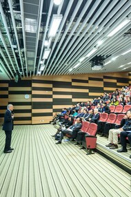 A man conducting his presentation and exercising his public speaking skills in an auditorium filled with people
