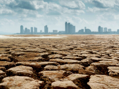 Dry, cracked ground stretches toward a distant megalopolis on the horizon