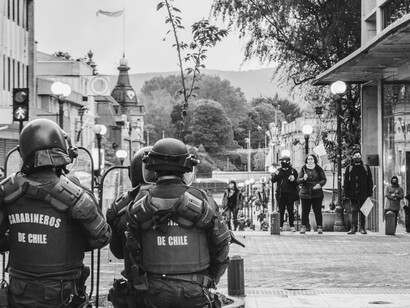 Black-and-white photograph of armored police officers stationed on the street