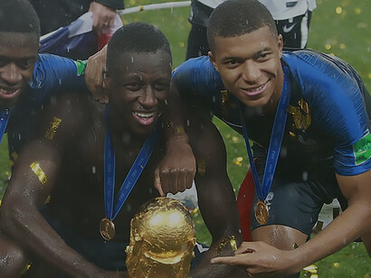 French footballer Benjamin Mendy, alongside teammates Ousmane Dembélé and Kylian Mbappé, proudly holds the FIFA World Cup Trophy after the final match on July 15, 2018