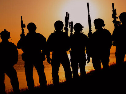 Soldiers holding their weapons against an abstract orange background