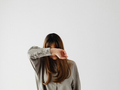 Woman in a gray long-sleeve shirt covering her face — a visual metaphor for confronting fear, embracing inner transformation, and finding resilience within