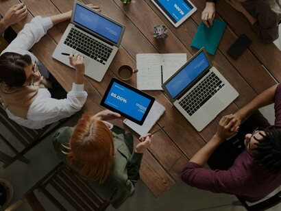 People discussing at a table with laptops