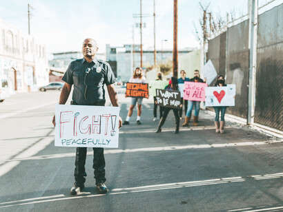 A policeman holds up a sign to fight peacefully