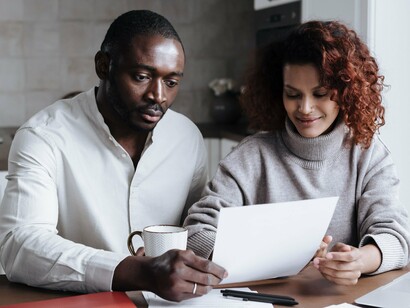 A couple thoughtfully reviewing financial documents together, representing the importance of shared responsibility in building a secure future