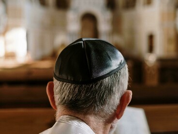 A man in a kippah sits in prayer while reading the Bible