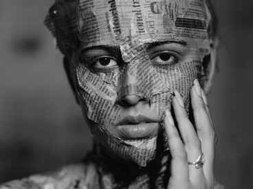 Manchetes e textos espalham-se pelo corpo da mulher, deixando livres apenas os olhos, a boca e o nariz. Ainda cercada por discursos, permanece a possibilidade de olhar e respirar criticamente. Em meio a informação e saturação, o mundo contemporâneo parece exigir constante filtragem do real.