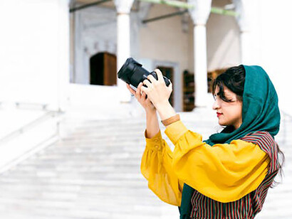 Amidst the city's beauty, a young tourist woman, her hijab adding grace to her attire, explores with a camera in hand, embracing the sights around her