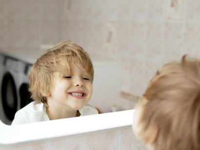 Un bambino si guarda allo specchio contento.  I bambini iniziano a riconoscere e identificare le proprie emozioni, differenziandole da quelle degli altri