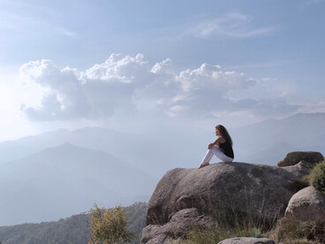 A woman sitting on a mountain, representing the clarity and emotional balance that mindful movement can cultivate