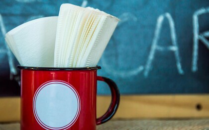 Guardanapos guardados numa caneca vermelha, à espera de uso como tantas presenças silenciosas que ocupam espaço na rotina sem realmente cumprir a função