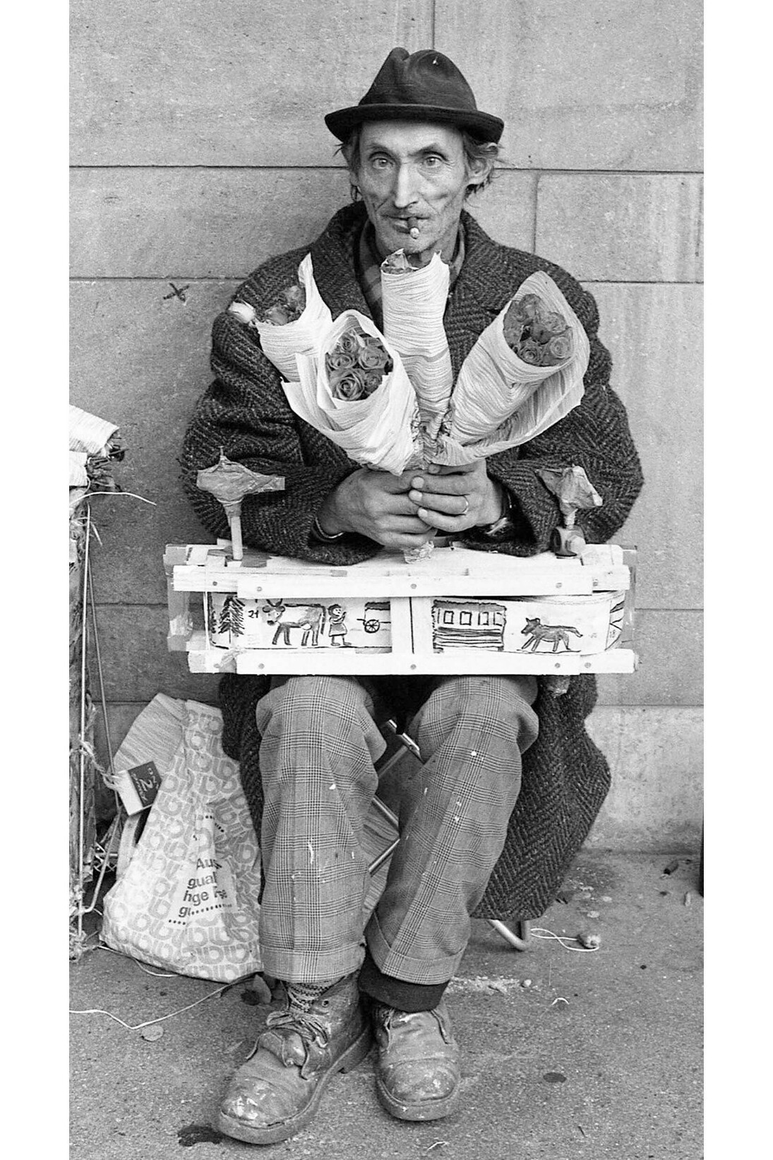 Photo by Eveline Meeuwse, Hans Krüsi (1920–1995) selling flowers at the Bahnhofstrasse in Zurich, with a “cow machine” on his lap, Zurich, Switzerland, 1978, Black and white photograph, 11.6 x 8.5" © Eveline Meeuwse