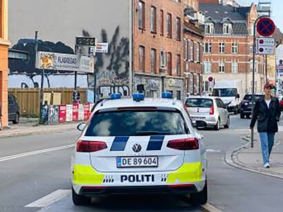 In Nørrebro, Copenhagen, two women stroll by a police car, capturing a snapshot of urban life and community interaction