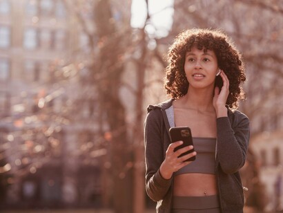 Mulher caminha enquanto ouve música. Reconhecer o poder transformador da música em nossas vidas é fundamental. Ela não apenas proporciona prazer, mas também oferece um meio de conexão com nossas emoções e com os outros