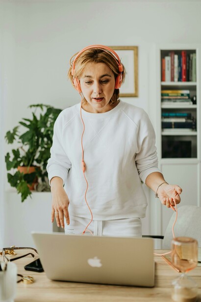 A woman works out at home wearing headphones, combining music and movement while passively learning a new language