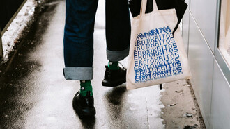 Una chica sostiene su 'tote bag' blanca. 'Tote' viene del verbo 'to tote', que significa «llevar»