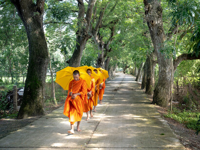 The Buddist monks carry umbrellas as they walk peacefully, with kindness