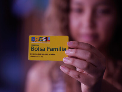 Smiling broadly, this Bolsa Família recipient showcases the card that represents more than just financial aid, it signifies hope and progress for many families struggling to make ends meet