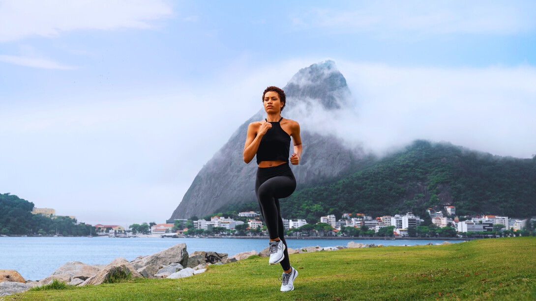 A woman jogging along a scenic waterfront, representing the uplifting impact of regular movement on mental well-being