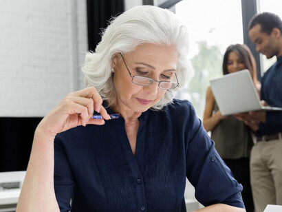 An experienced elder businesswoman engaging in her work at the office, showcasing the active participation of seniors in professional environments