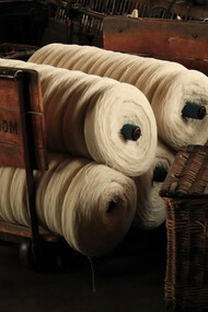 Several rolls of yarn made from plant-based fibers resting on a wooden cart, showcasing natural materials used in sustainable fashion