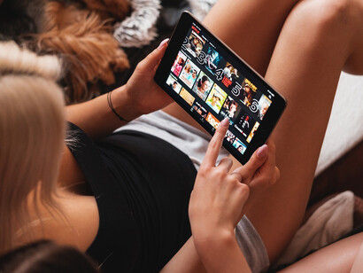 A girl looking at a tablet, choosing what to watch