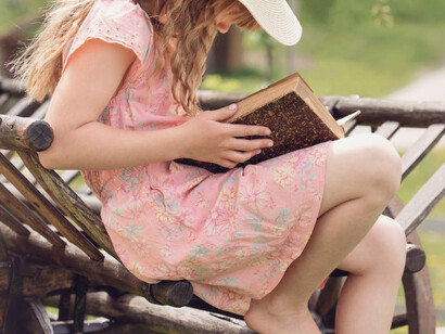 Bambina legge serena un libro in un parco 
