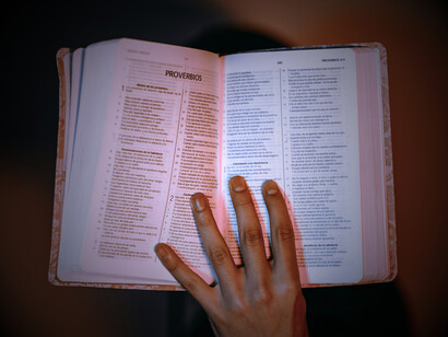 A hand showing an open Bible, illustrating the difference between simply professing faith and actually practicing it