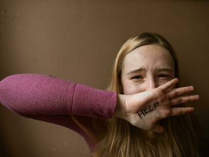 The word “Help” written on a woman’s palm symbolizes the silent suffering caused by emotional abuse