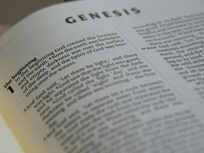 A close up of and Bible opened in the Genesis chapter
