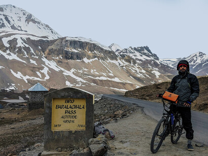 A man cycling along a mountain trail, surrounded by breathtaking scenery