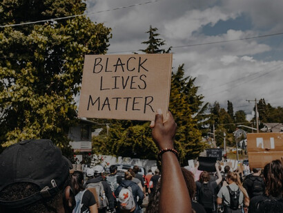 In the daytime, people fervently display brown wooden signs with the powerful message "Black Lives Matter"