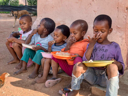 A group of African children eating in the yard, highlighting the challenges of famine and malnutrition