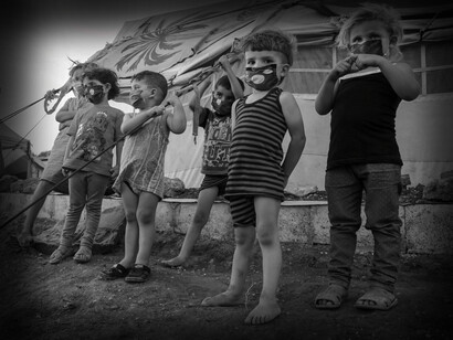 Children refugees during COVID, stand with their masks on outside of the tents at the Idlib refugee camp, Idlib Governorate, Syria
