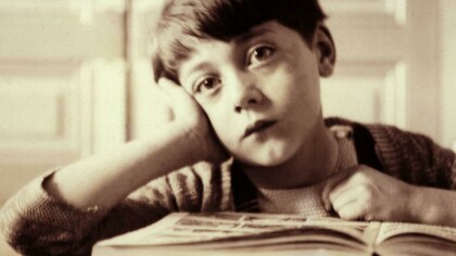 Un niño aburrido frente a un libro de texto
