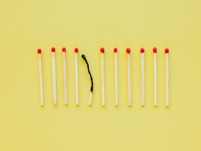 Extinguished matchsticks lying near unlit ones, representing the aftermath of overextension