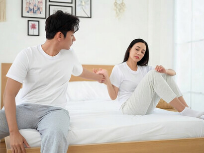 A couple sits in silence on opposite sides of the bed, revealing the growing emotional distance in their relationship