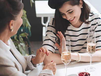 Two women indulging in a convivial moment, savoring a glass of wine at the elegantly set table