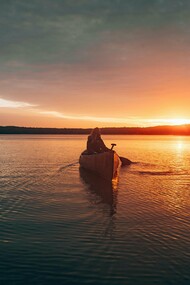 A woman drifting through Ely Lake, Minnesota beneath the fading Minnesota sky, reflecting the deep connection between nature, solitude, and healing