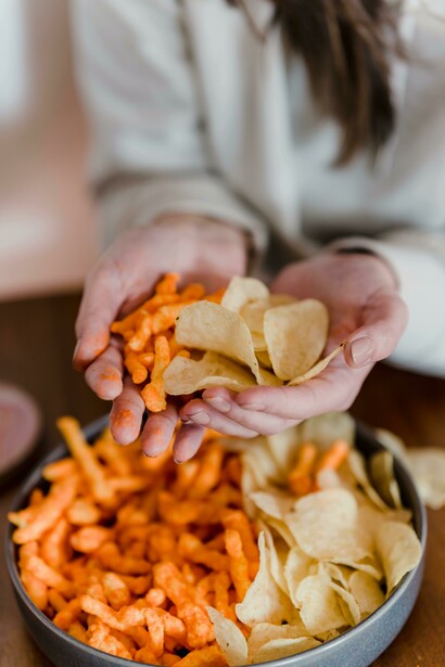 Close-up of a woman holding crisps, symbolizing processed food cravings and snack culture