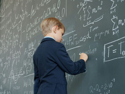 Ce garçon effectuant des calculs sur le tableau illustre l'intégration des puissances locales (mentales et corporelles) dans des régimes d’organisation systématiques qui permettent une pensée et une résolution de problèmes avancées