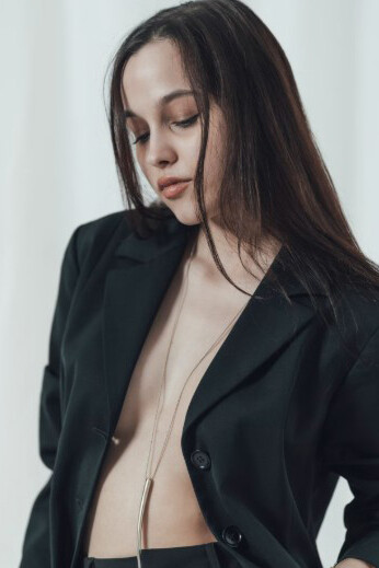 Dressed in only a sleek black suit, a woman poses fearlessly for the camera